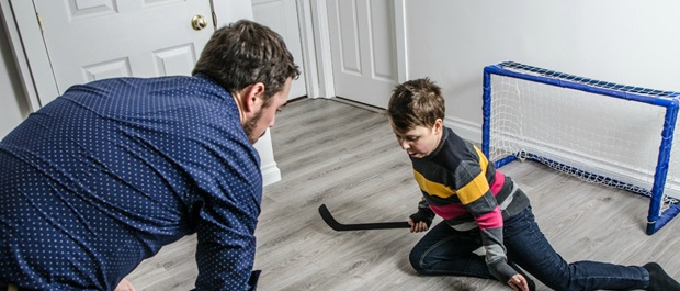 A man plays floor hockey with his son