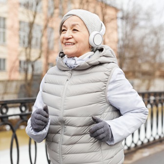 Older woman walking in the cold with headphones.