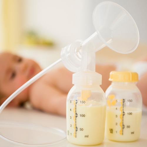 Baby Looking at Breast Pump and Bottle Full of Milk