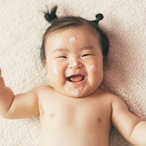 Happy baby with lotion.