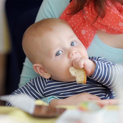 Infant eating first solid foods.