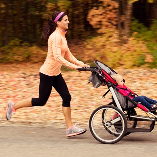 Mother jogging in the park with her infant.