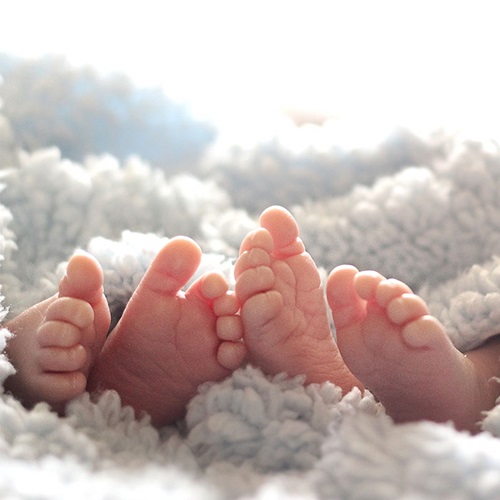 Newborn twins feet under a blanket.