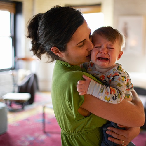 Woman Holding and Comforting Crying Baby with Croup
