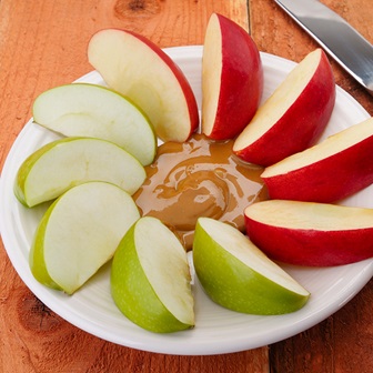 Sliced red and green apples and peanut butter