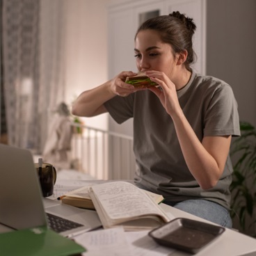 College age girl eating in front of her computer