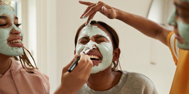 Young women laughing while putting on a face mask