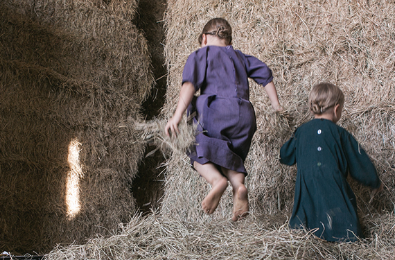 kids playing on hay bails in a barn